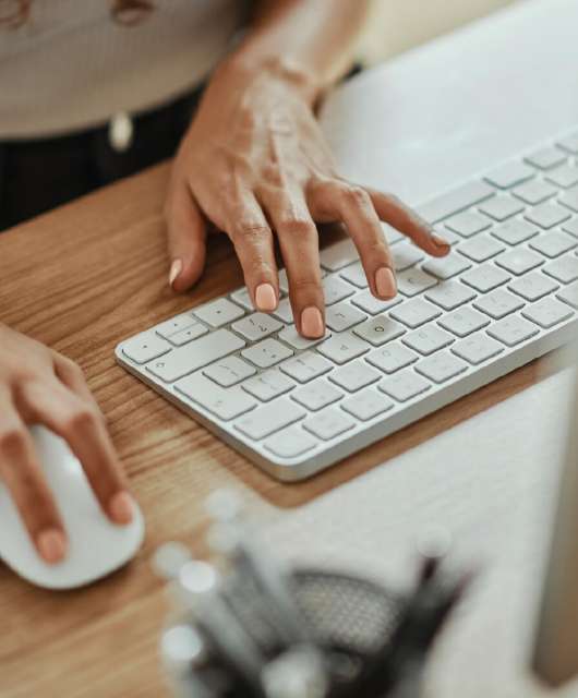 Person typing on a keyboard with one hand and mouse in the other.