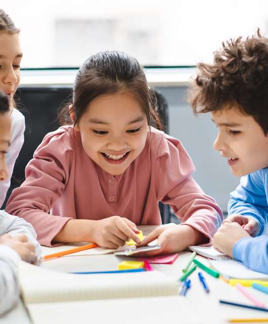 School kids learning over a table looking at a smartphone.